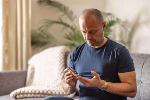 Adult checking blood sugar levels with a glucose meter during routine monitoring.