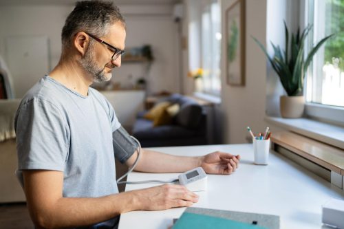 Adult measuring blood pressure at home using an automatic digital blood pressure monitor.